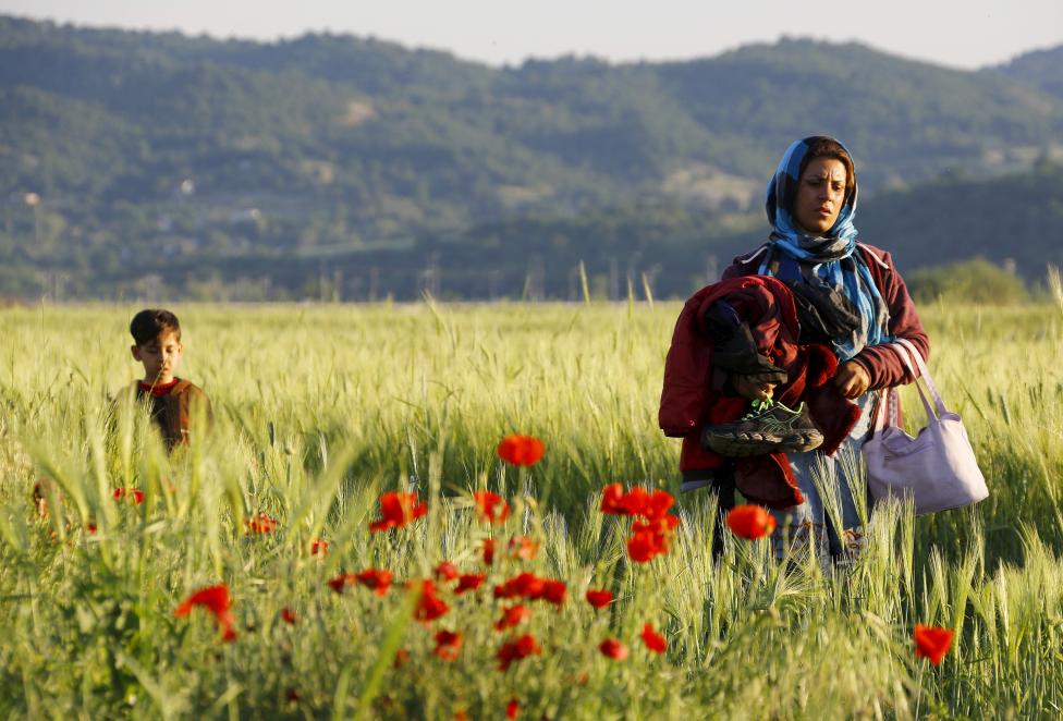 An Afghan immigrant, followed by her child, walks through a field close to the Greek-Macedonian border in an attempt to flee to Macedonia from the border village of Idomeni in Kilkis prefecture, May 13, 2015. REUTERS/Yannis Behrakis