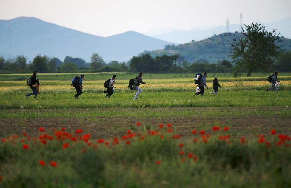 A group of Syrian immigrants run on a field towards Greece's border with Macedonia in Kilkis prefecture, May 14, 2015. REUTERS/Yannis Behrakis