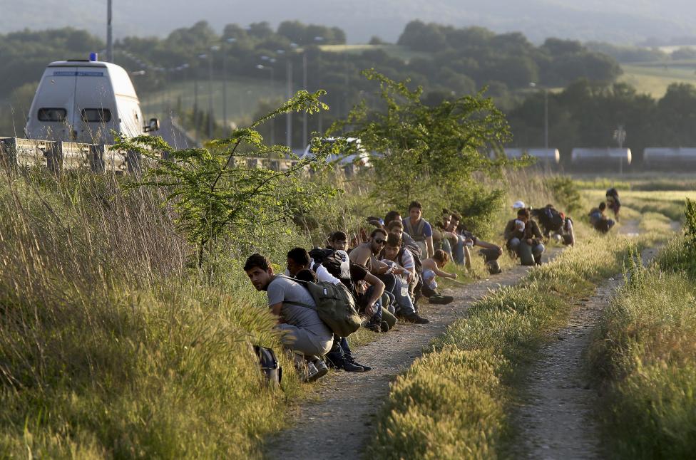 A group of Syrian immigrants hide as a Greek police patrol van drives on the asphalt road next to them near the border with Macedonia in Kilkis prefecture, May 14, 2015. REUTERS/Yannis Behrakis
