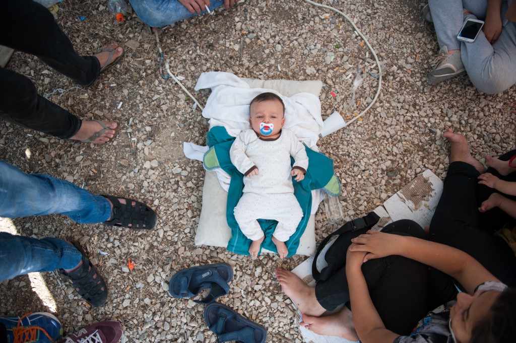 A Syrian baby lies in the floor of Kara Tepe camp. The family has no milk to feed the child and no money to buy. The baby's father, 26 year old Deshevan said: I am here with my family: my wife, my child and my sister. We are part of a group of 19 people from Syria. We have been in the camp for five days so far. There is nothing here for us. All 19 of us sleep in one tent. Everywhere you see dirty water and rubbish. There are no toilets, no cleanliness. There is one small tap for drinking water and washing ourselves. There is not enough food for everyone, but this is not important to us. What we need  but dont have  is information about our papers. We were given a piece of paper by the port police, but since then we have been waiting here and have heard nothing. Nobody tells us anything. There is no one responsible to give us any information, and we dont know what to do. No authority, no police, no information, nothing. There is no milk for the baby  no one has given us any  so we have to go to the supermarket and buy it. We dont have enough money, but for the baby we will find a way.