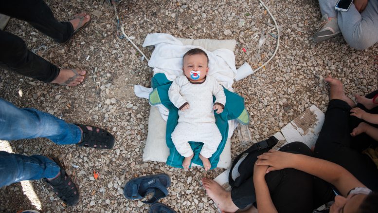 A Syrian baby lies in the floor of Kara Tepe camp. The family has no milk to feed the child and no money to buy.

The baby's father, 26 year old  Deshevan said:  I am here with my family: my wife, my child and my sister. We are part of a group of 19 people from Syria.

We have been in the camp for five days so far. There is nothing here for us. All 19 of us sleep in one tent. Everywhere you see dirty water and rubbish. There are no toilets, no cleanliness. There is one small tap for drinking water and washing ourselves.

There is not enough food for everyone, but this is not important to us. What we need  but dont have  is information about our papers. 

We were given a piece of paper by the port police, but since then we have been waiting here and have heard nothing. Nobody tells us anything. There is no one responsible to give us any information, and we dont know what to do. No authority, no police, no information, nothing.

There is no milk for the baby  no one has given us any  so we have to go to the supermarket and buy it. We dont have enough money, but for the baby we will find a way.